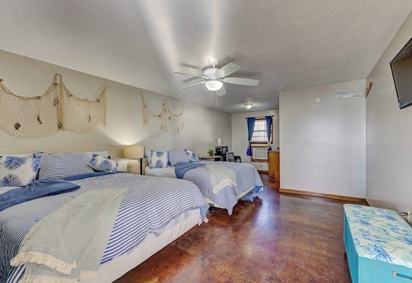 A bedroom with two beds, a ceiling fan, and a window with curtains.