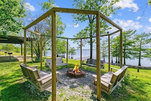 A wooden gazebo with a fire pit in the center, surrounded by seating.