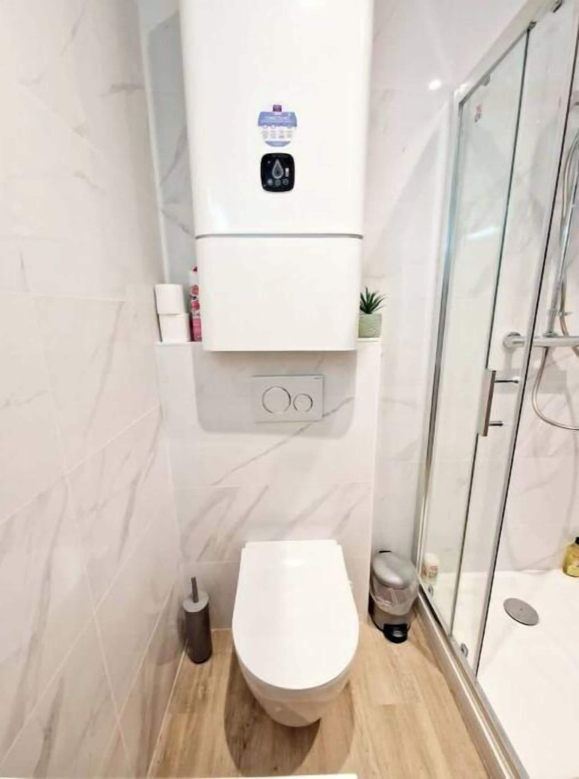 Moderni kylpyhuone, jossa on wc, lasinen suihkuseinä ja marmorikuvioitu seinä.