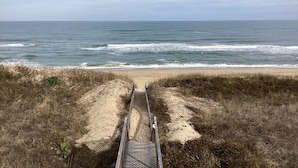 A beach path leading to the ocean with a clear view of the sea and sky.