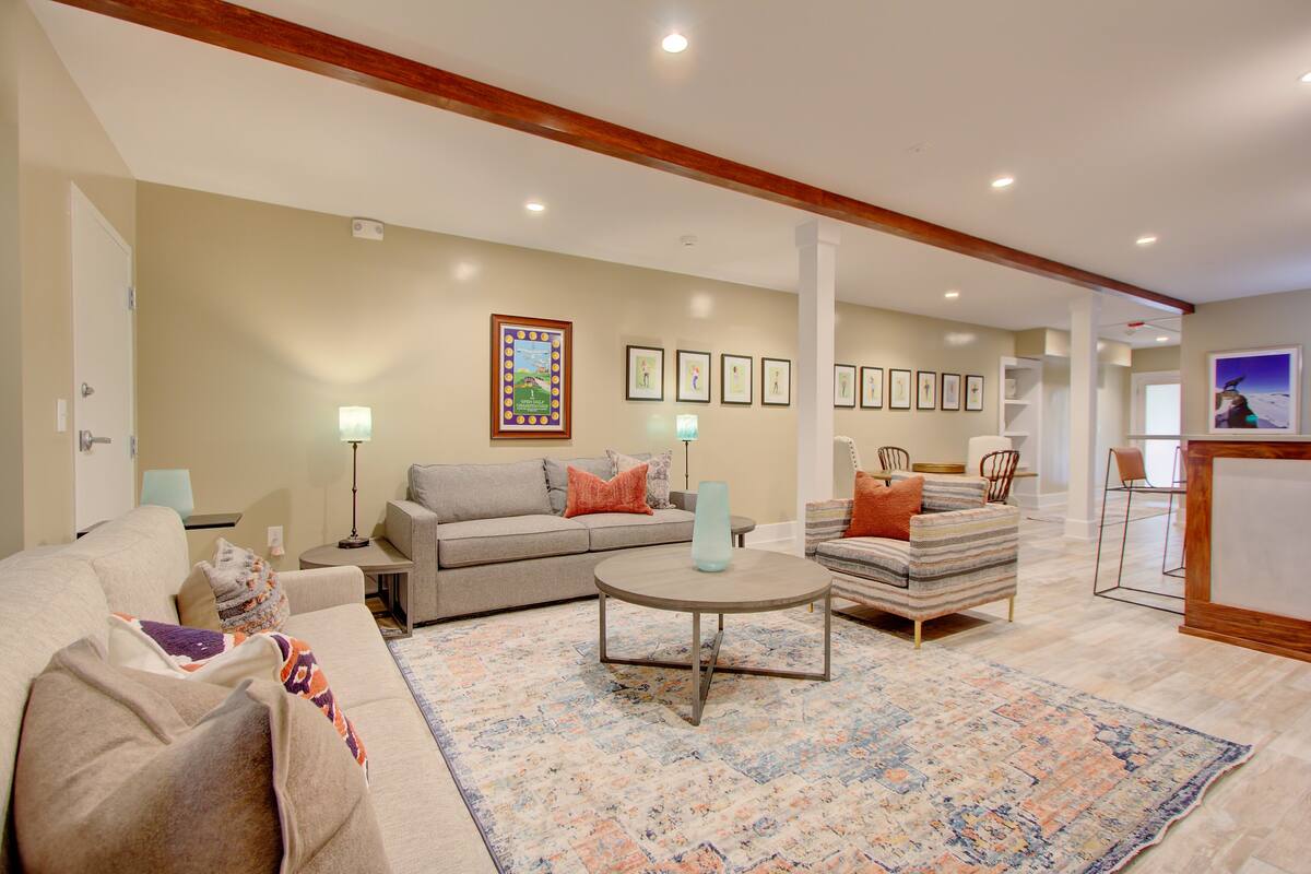 A living room with a sofa, armchair, coffee table, and a patterned rug.