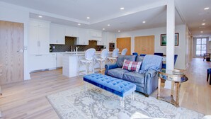 A modern kitchen with white cabinets, a central island, and a dining area with white chairs. - The Charleston Chestnut Mansion (Charleston)