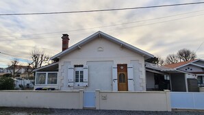 Un edificio de dos plantas con fachada blanca, una puerta de madera y un pequeño porche.