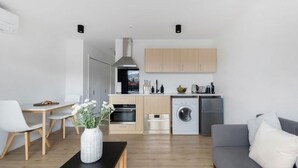 Een moderne keuken met houten kastjes, een inbouwoven en een wasmachine.