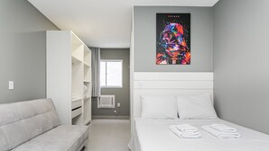A modern hotel room with a bed, a sofa, a wardrobe, and a window. - New studio near Beiramar Shopping #HKS14 (Florianópolis)