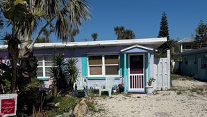 A single-story house with a porch, a small attached garage, and a gravel driveway. - Sizzling Hot Summer so stay by the Beach (New Smyrna Beach)