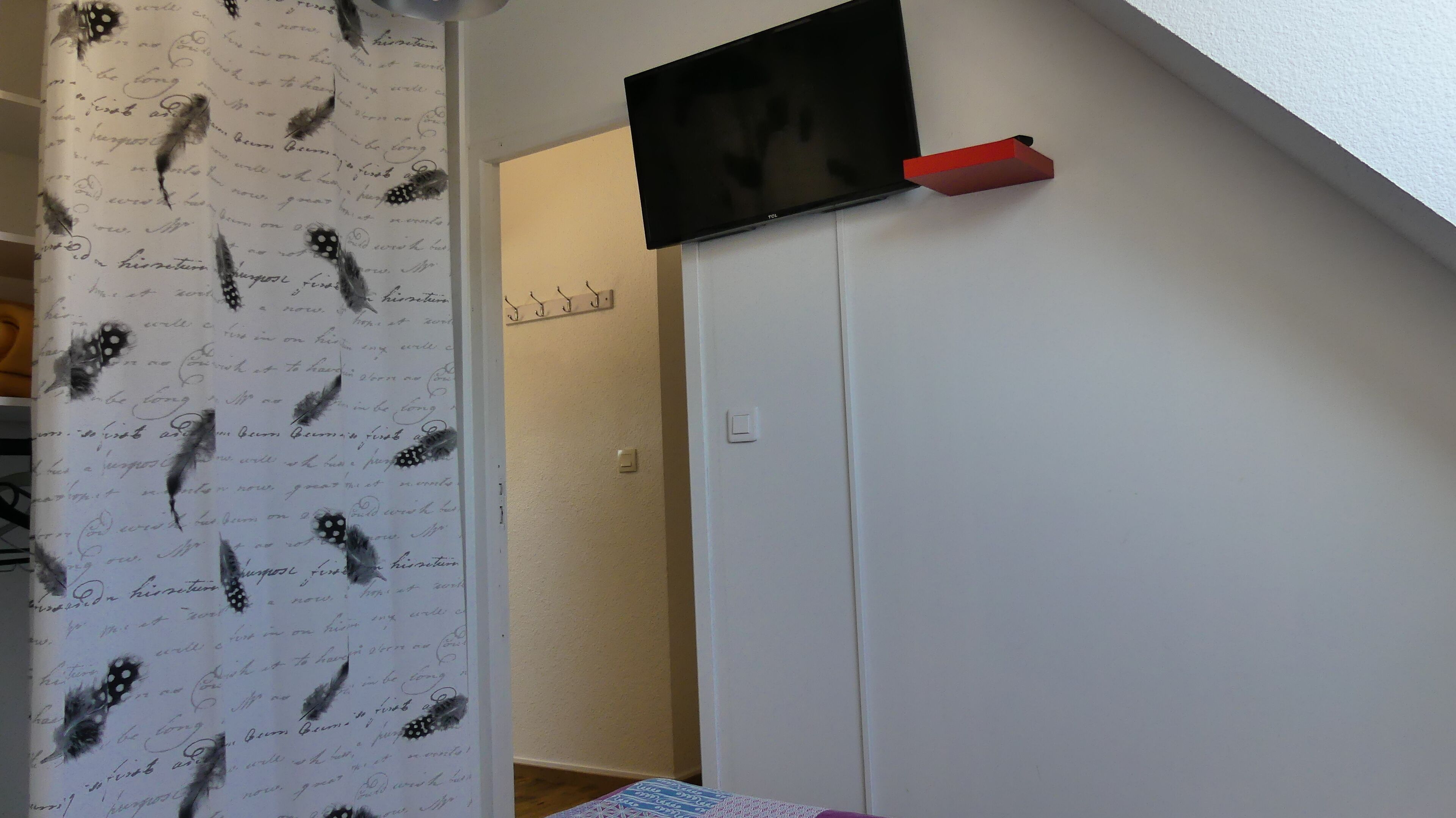 Un escalier mène à une pièce où est fixée un téléviseur à écran plat au mur.