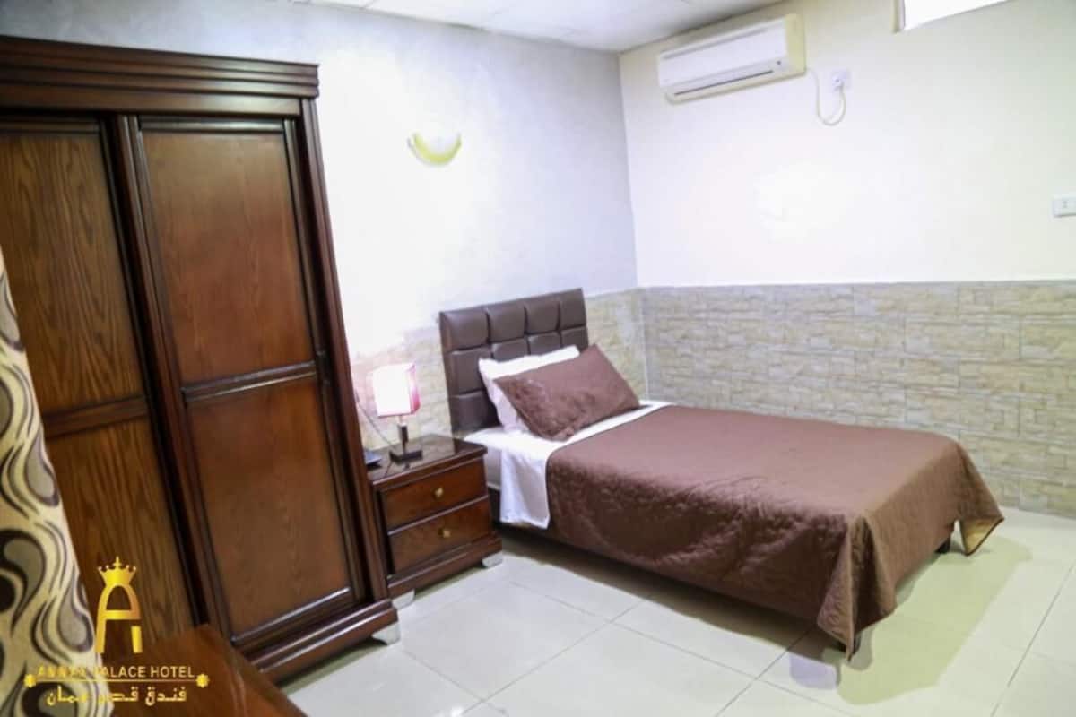 Quarto com cama, mesa de cabeceira, guarda-roupa e ar-condicionado fixado na parede.