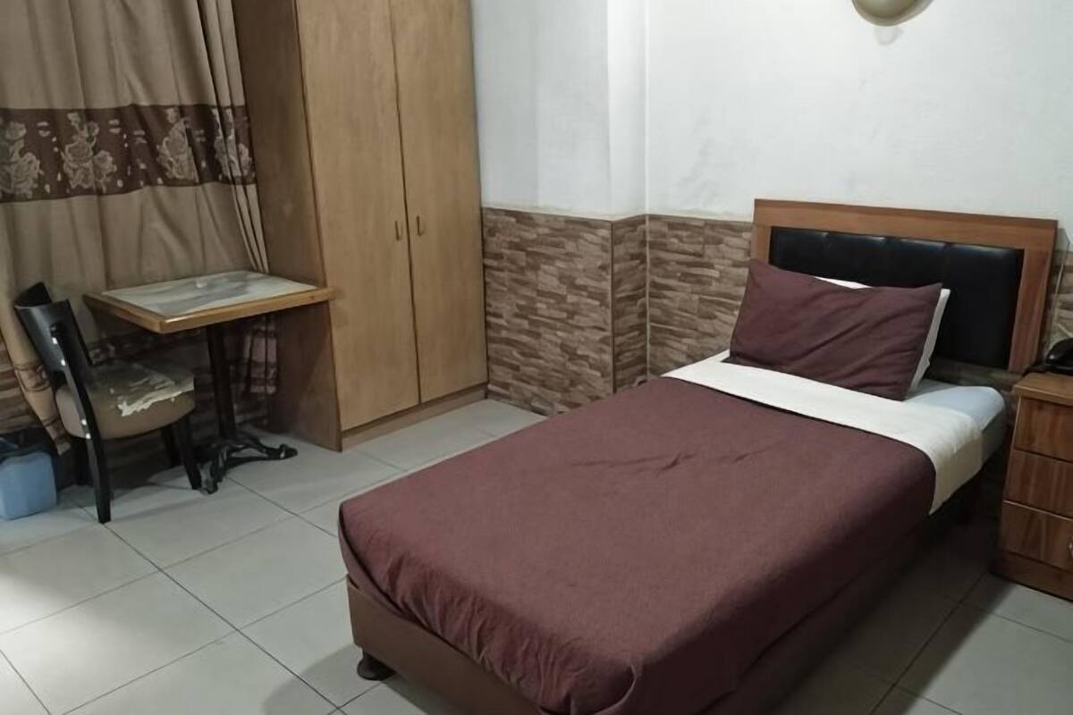 A bedroom with a bed, a desk, a chair, and a wardrobe.