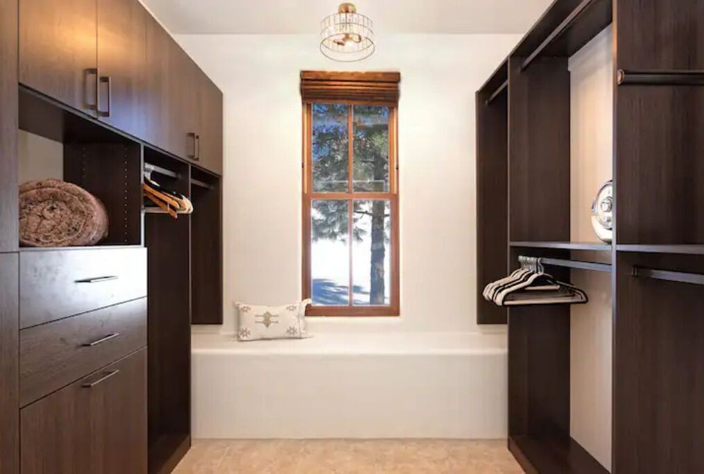 A walk-in closet with a large window, built-in shelves, and a hanging rod.