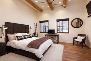 Relax in this serene bedroom with a large bed, TV, and comfortable chair.