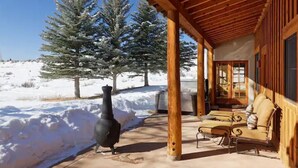 A wooden cabin with a covered porch, a fireplace, and a seating area with outdoor furniture.