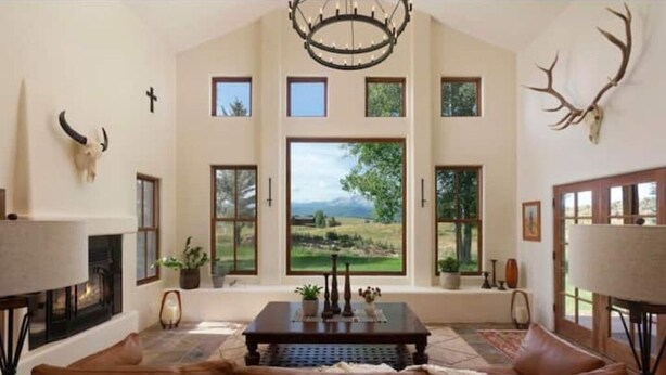 A spacious living room with a large window, a fireplace, and a chandelier.