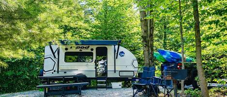 A recreational vehicle (RV) with a kitchen area, seating, and a covered area for a canoe.