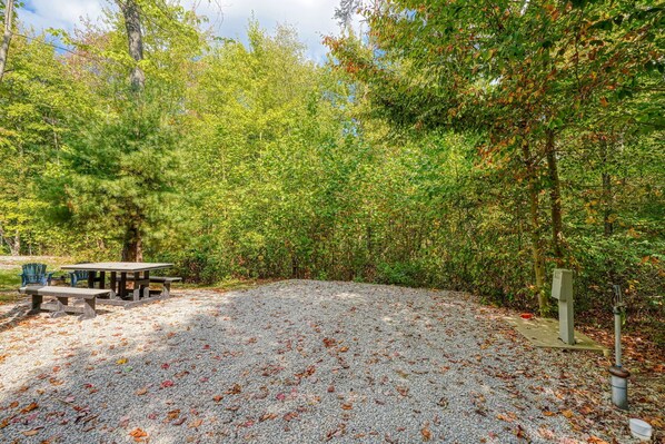 A picnic area with a table and benches, surrounded by trees and covered with gravel.