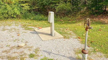A concrete structure with a metal object on a gravel surface, surrounded by grass and trees.