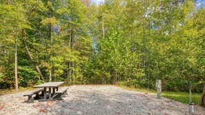 A picnic area with a table and benches, surrounded by trees and gravel. - RV Site 2 of 4: Lot rental only; RVs not provided. (South Bloomingville)