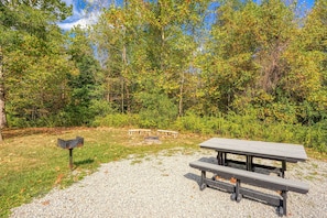 Enjoy al fresco dining and cozy gatherings in this peaceful outdoor space surrounded by lush trees and shrubs.