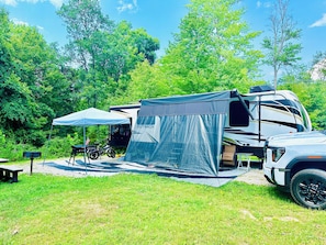 Experience the great outdoors with a spacious RV and a cozy tent, perfect for a camping getaway.