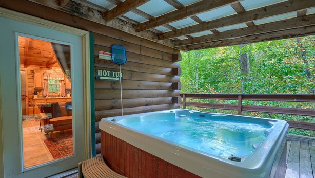 Une cabane en bois avec un jacuzzi, un panneau indiquant la direction du jacuzzi, et une vue sur la forêt environnante.