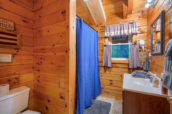Baño de cabaña de madera con inodoro, lavabo y zona de ducha.