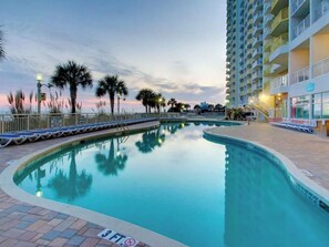 A swimming pool with a 3 ft depth marker, surrounded by palm trees and a hotel building with balconies. - Renovated Bay Watch 812 - 2 Bedroom/2 Bath (North Myrtle Beach)