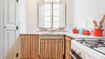 Una cocina con estufa blanca, ventana con cortinas y salpicadero de azulejos.