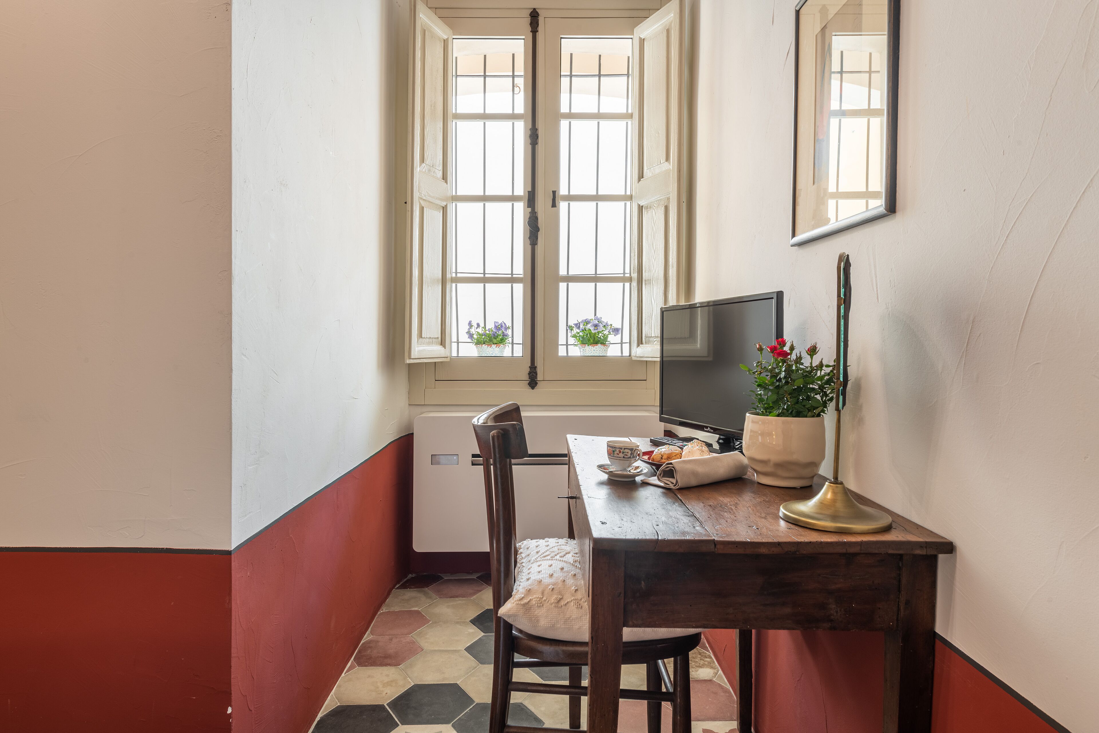 Un petit coin repas avec une table en bois, une chaise, un téléviseur et une plante en pot.