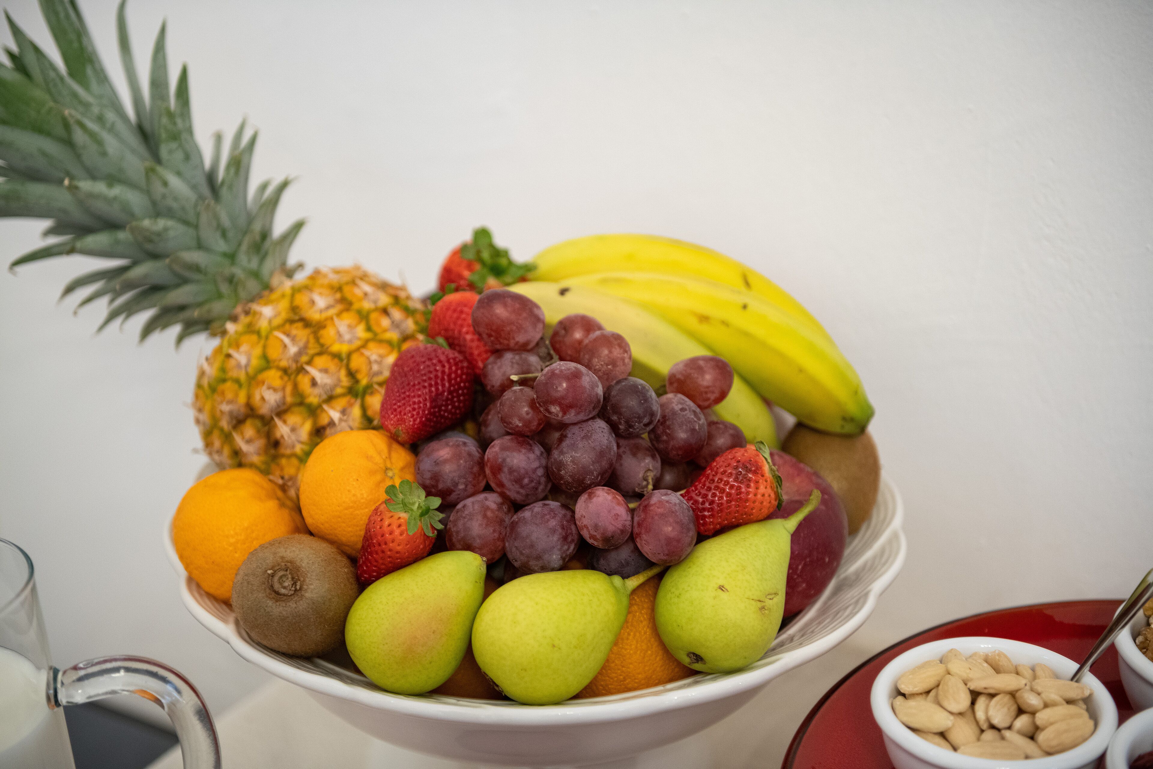Un bol amb assorted fruits: pineapple, plàtans, maduixes, raïms, taronges i peres.