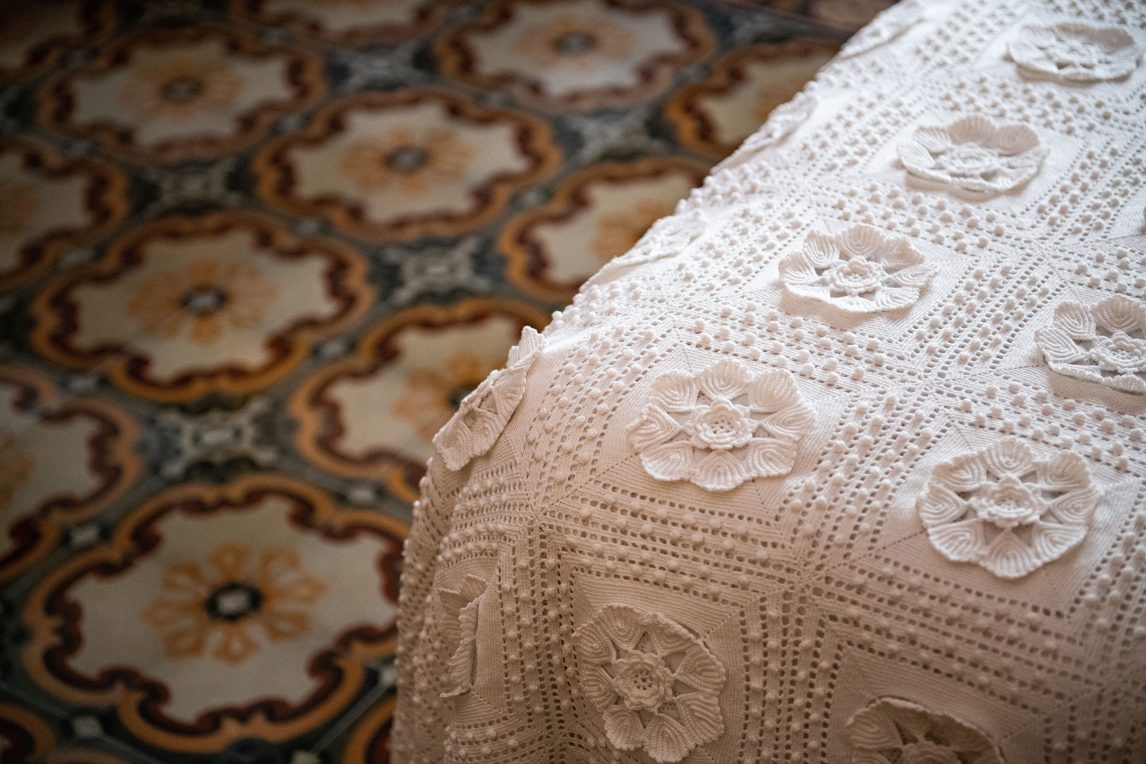 A close-up of a crocheted fabric with floral patterns and a detailed, textured surface.