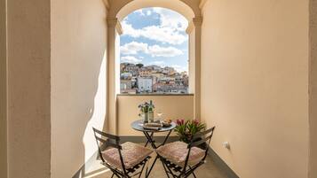 Un balcone con tavolo, sedie e vista su un panorama urbano attraverso un arco.