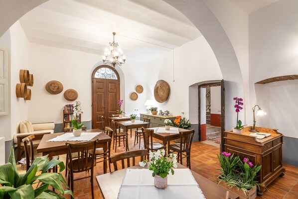 A spacious dining area with wooden furniture, a chandelier, and various decorative items on the walls. - Palazzo Cherchi (Dorgali)