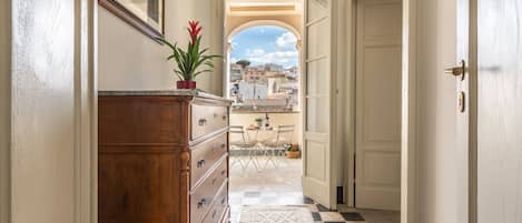 A hallway with a wooden dresser, a patterned rug, and a view of an outdoor patio with a table and chairs.