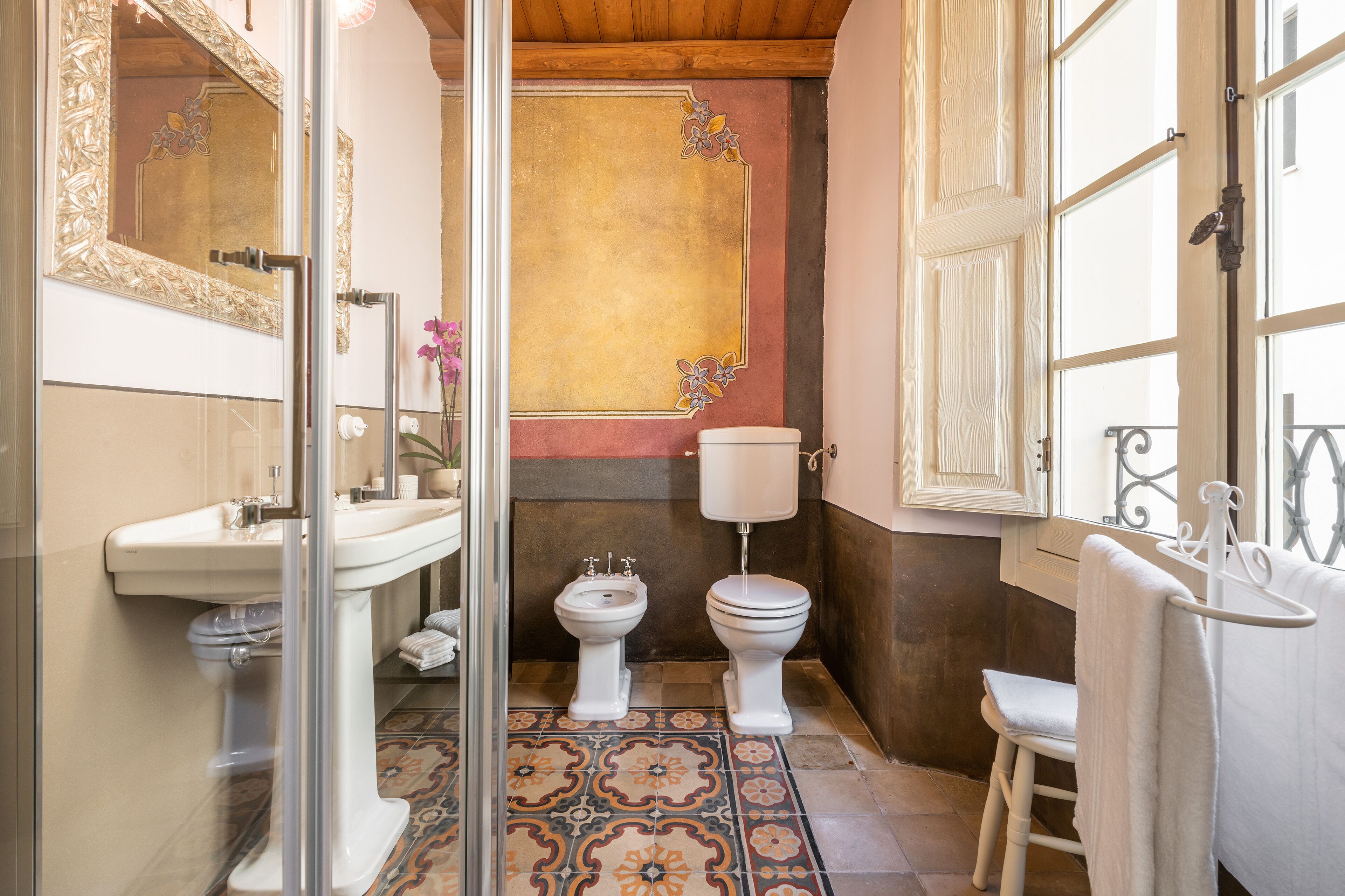 Un baño con cabina de ducha de vidrio, un lavamanos blanco, un inodoro y un bidé.