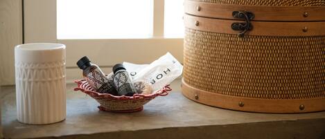 A wicker suitcase, a white ceramic mug, and a woven basket with toiletries on a windowsill.