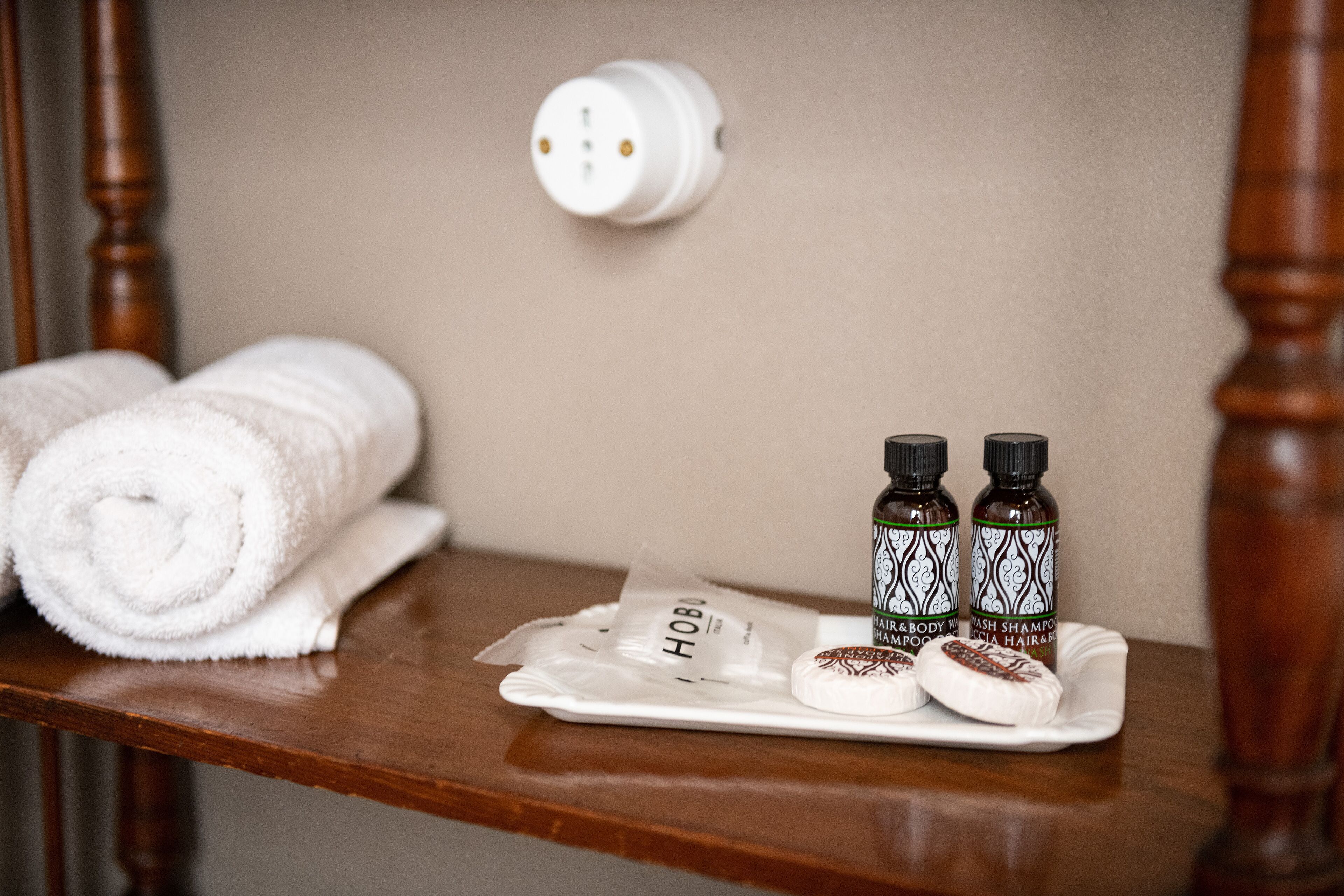 A wooden shelf with a rolled white towel, two bottles of hair and body wash, and a small package labeled "HOB".