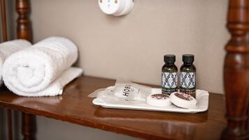 A wooden shelf with a rolled white towel, two bottles of hair and body wash, and a small package labeled "HOB".