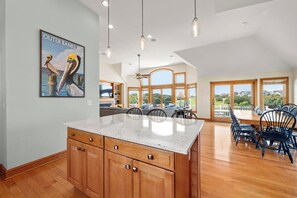 A spacious kitchen with a large island, wooden cabinets, and a view of the outdoors.