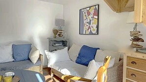 Une pièce chaleureuse avec un canapé, une petite table avec des verres, une lampe et une œuvre d’art murale.
