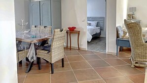 Il y a un coin repas avec une table, des chaises et un buffet. La pièce adjacente contient un lit.