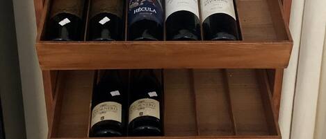 A wooden wine rack with multiple shelves, each holding bottles of wine. The top shelf has a label reading "Palacio de Arguenza."