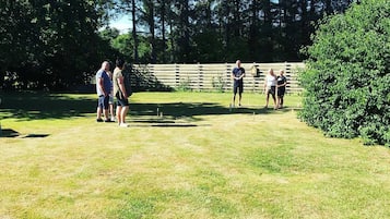 Ruohikkoalue ulkona, jossa on puinen aita ja taustalla näkyy puita.