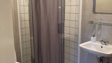 Un baño con cabina de ducha, inodoro y lavamanos.