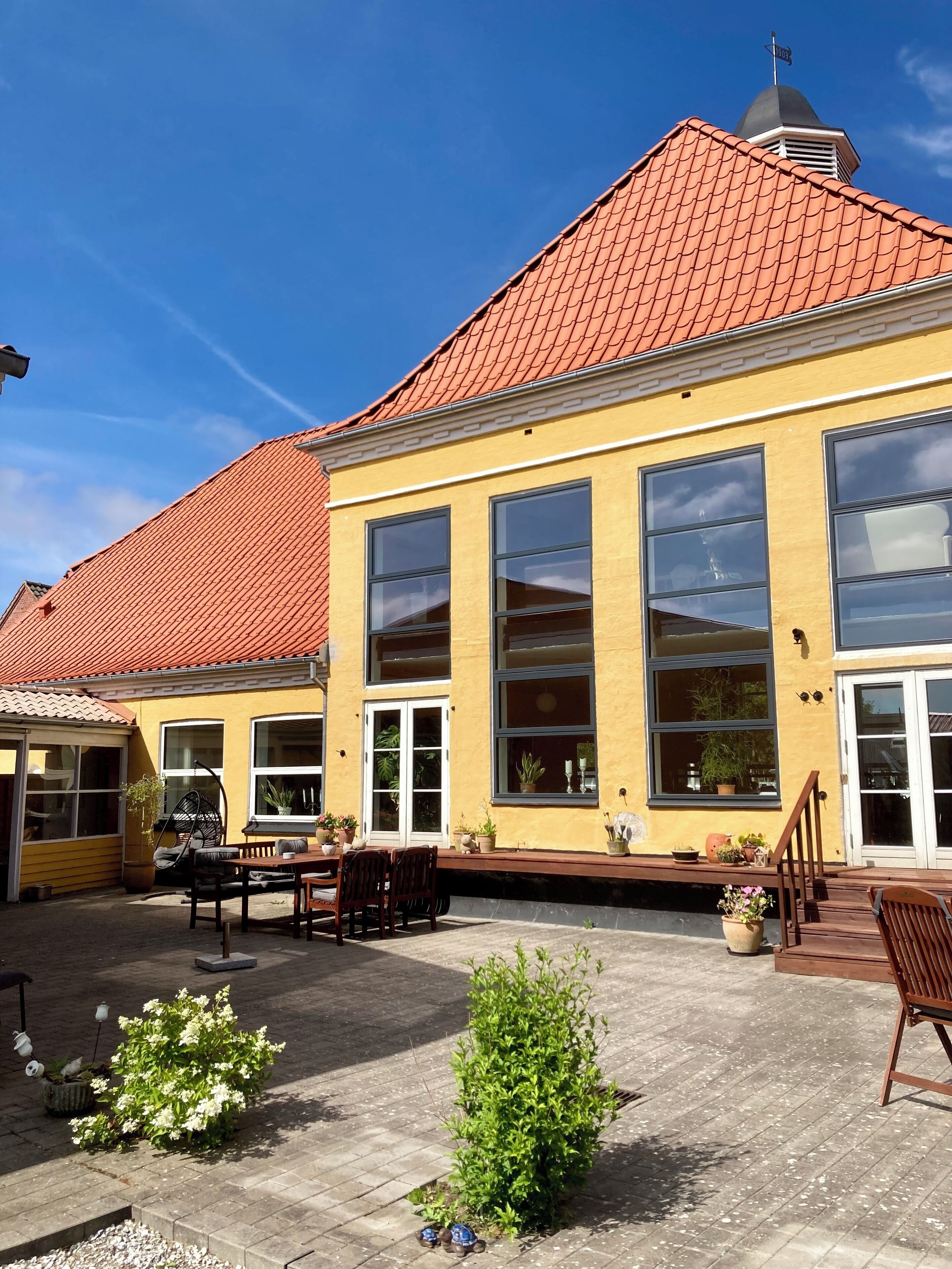 A yellow building with large windows and a red-tiled roof.