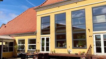 A yellow building with large windows and a red-tiled roof.