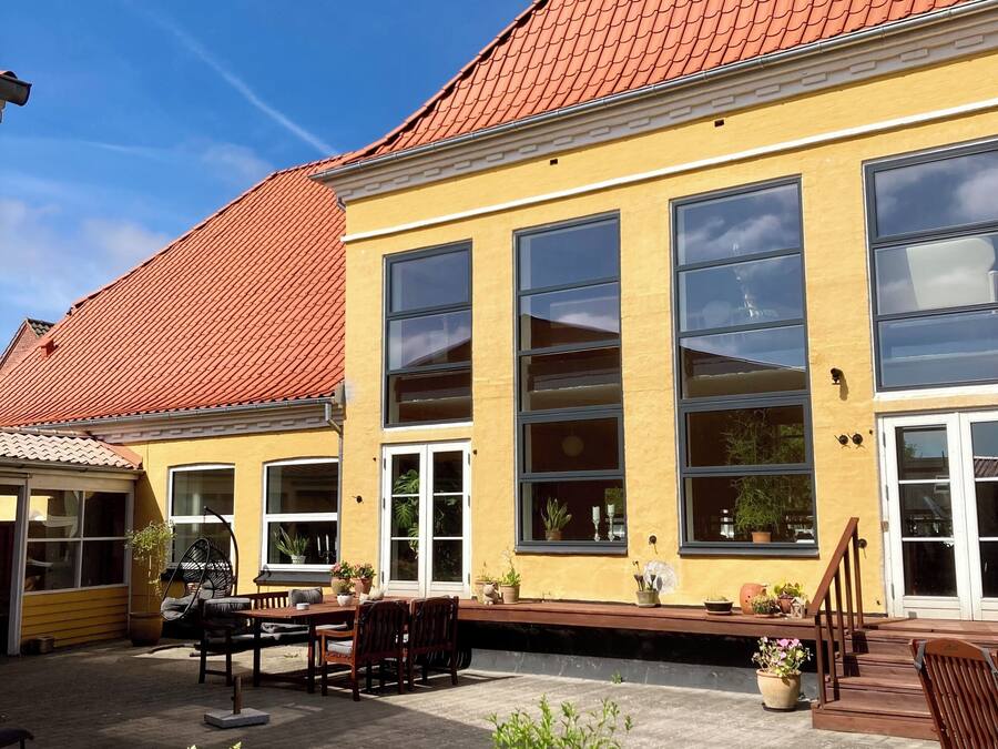 A yellow building with large windows and a red-tiled roof.