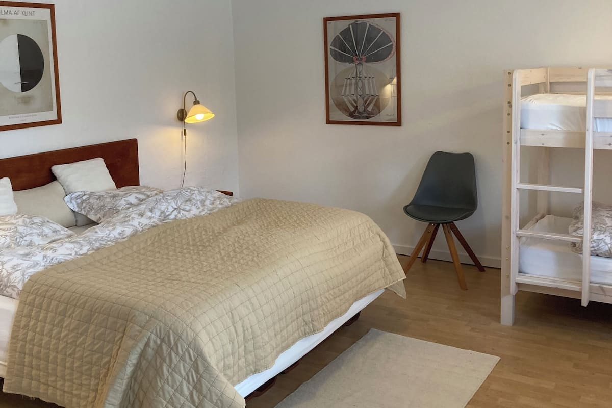 Ein Schlafzimmer mit einem Bett, einem Sessel, einem Etagenbett und zwei Wandlampen.