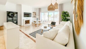 Un salon moderne avec un canapé blanc, un coin repas et une cuisine.