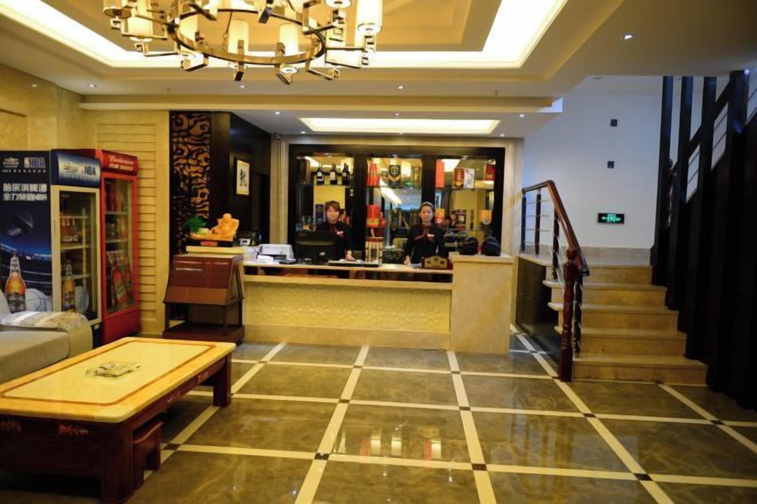 A hotel lobby with a reception desk, a staircase, and a check-in counter.