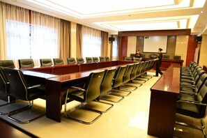Uma sala de conferências com uma mesa comprida e cadeiras, uma tela de projetor e uma área para apresentações.